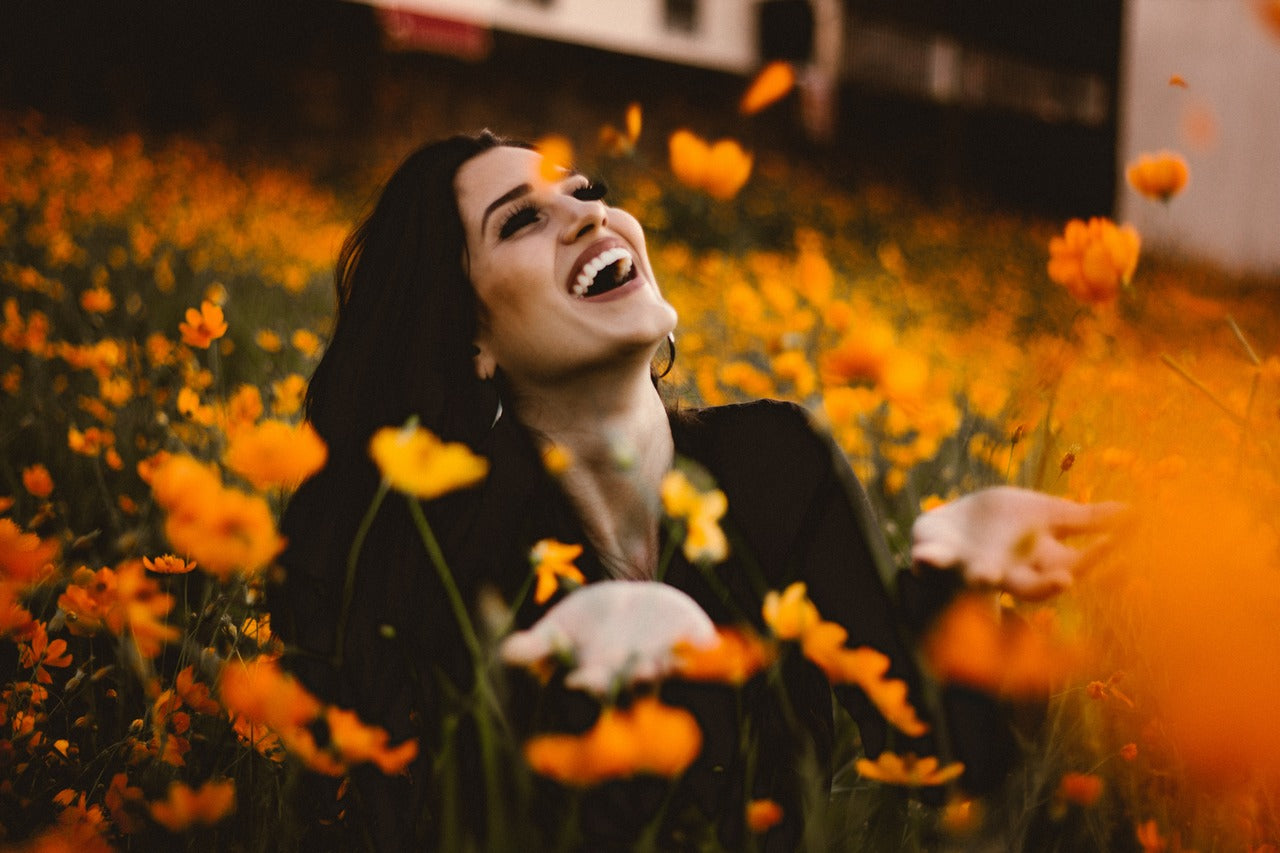 woman sitting in a flower field and laughing over gut health