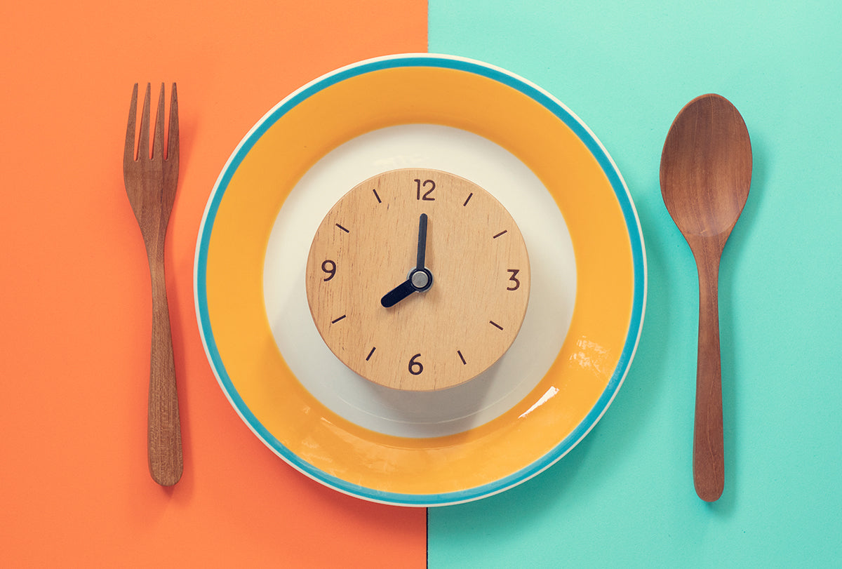 plate with fork and spoon and clock intermittent fasting